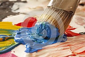Close up of paintbrush picking blue color from an artist palette. Colorful image from an artistâ€™s studio or a school showing cre