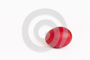 Close-up painted red egg settled in the middle of white background.