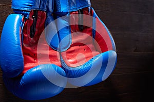 Close-up of the pair of blue and red boxing gloves hanging in a wooden wall.
