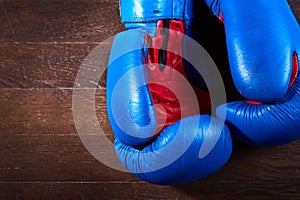 Close-up of a pair of boxing blue and red gloves hanging on the wooden wall.