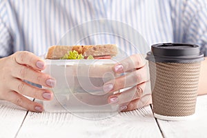 Close up on pair of female hands removing a healthy wholesome wholemeal bread ham sandwich from her lunch box during lunch break