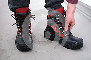 Close-up of a pair of new high black work boots made of genuine leather with a reinforced cape on the man`s feet, trying on new