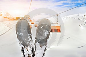 Close-up pair of skis on mountain winter resort with ski-lift and beautiful winter mountain panoramic scenic view