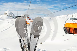 Close-up pair of skis on mountain winter resort with ski-lift and beautiful winter mountain panoramic scenic view