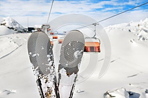 Close-up pair of skis on mountain winter resort with ski-lift and beautiful winter mountain panoramic scenic view