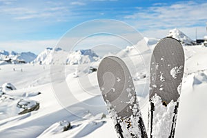 Close-up pair of skis on mountain winter resort with ski-lift and beautiful winter mountain panoramic scenic view