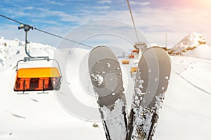 Close-up pair of skis on mountain winter resort with ski-lift and beautiful winter mountain panoramic scenic view. Winter extreme