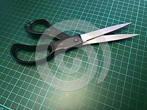 Close up of a pair of stainless steel metal scissors on a cutting mat