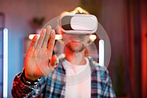 Close up of palm of young guy in VR goggles working in augmented reality while staying at home.