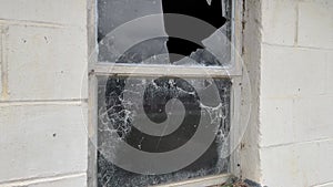 Close up pan of a spooky old concrete block building and busted window