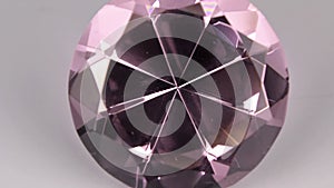 Close-up, panorama of a large pink rhinestone on a white background. Beautiful light reflection