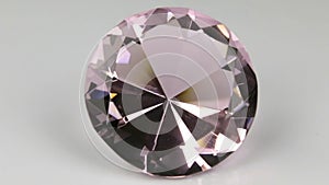 Close-up, panorama of a large pink rhinestone on a white background. Beautiful light reflection