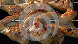 Close-up panorama of the spicy chicken wings on skewers frying above open fire