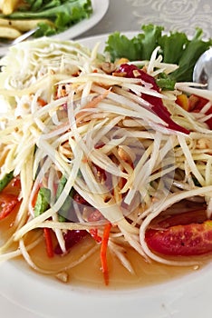 Close up Papaya salad with red tomatoes pieces served on white plate, Thai food tasty and delicious.