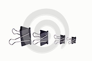 Close-up of paper clips of black color, of different sizes, from large to small. Isolated on a white background
