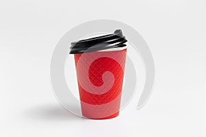 Close-up of paper cup with black plastic lid for coffee takeaway of red color isolated on white studio background