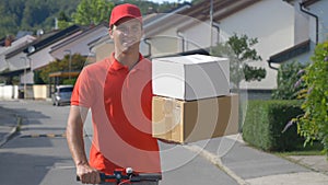CLOSE UP: Parcel delivery man holds two boxes in one hand while riding escooter. photo