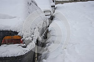 Close-up of parked cars covered in a thick layer of snow during a snowstorm