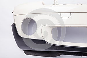 Close-up of a part of a car bumper on a white isolated background in a photo studio with a hole for a fog lamp after repair and