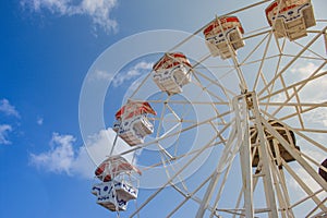 Close up part of colorful ferris wheel with blue sky in the background.
