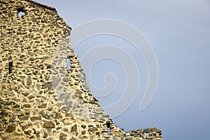 Close up of part of fortified wall of an ancient fortress against grey cloudy sky. Copy space.