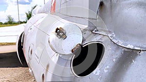 Close-up of part of the fuselage of an old military fighter jet, which has an open fuel system. The open tank of the aircraft, the