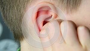 Close-up part of the head of a child, kid, scratches his ear with his hand, touches his finger inside, the concept of modern