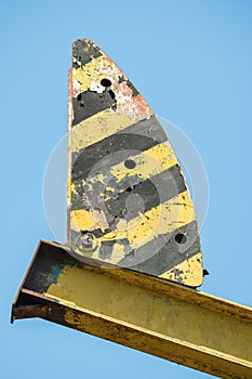 Close-up of part of an old abandoned oil rig with peeling paint. In the background is a blue sky. A concept of the