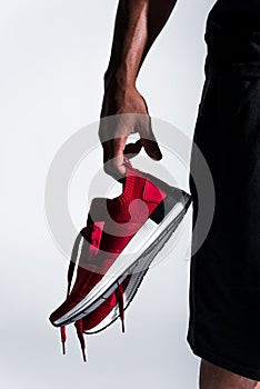 close-up partial view of african american sportsman holding sports shoes