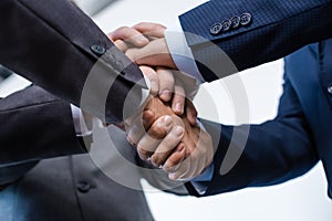 Close-up partial view of businesspeople in formal wear stacking hands together