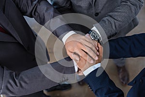 Close-up partial view of businesspeople in formal wear stacking hands together