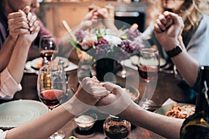 close-up partial view of people holding hands and praying