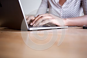 Close up partial woman sitting and typing on laptop computer in home office