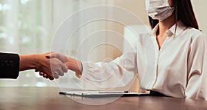 Close up of partnership handshake successful after negotiating business. woman wearing a mask that focuses on health. photo