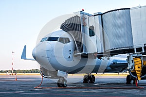 Close-up passenger jet plane parked to a boarding bridge and connected to an external power supply