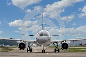 Close-up of a passenger plane on the taxiway at the airport against the backdrop of a beautiful cloudy sky, front view