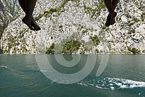 Close-up of passengers dangling their legs and feet from the railing and enjoying the scenery on the Komani Lake, Albania