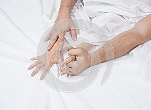 Close up of passionate couple hold hands during making intense love in bedroom, lovers enjoy hot sex on white sheet