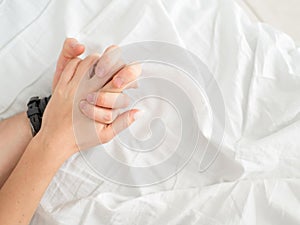 Close up of passionate couple hold hands during making intense love in bedroom, lovers enjoy hot sex on white sheet