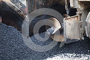 Close up of pavement machine laying fresh asphalt or bitumen. Road construction