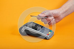 Close-up of payment machine buttons with human hand holding plastic card near by on yellow background