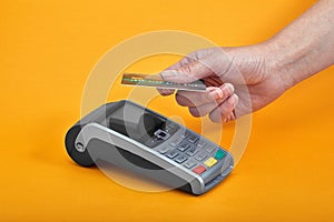 Close-up of payment machine buttons with human hand holding plastic card near by on yellow background