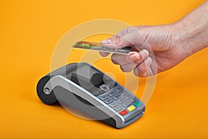 Close-up of payment machine buttons with human hand holding plastic card near by on yellow background