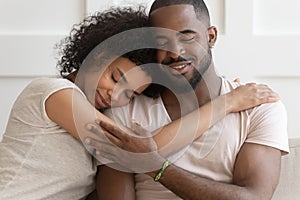 Happy African American couple cuddle hugging at home