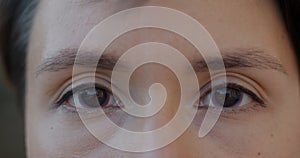 Close-up of peaceful female face and eyes with contact lenses looking at camera outdoors