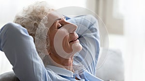 Close up peaceful older woman relaxing on cozy sofa