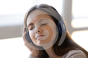 Close up peaceful woman in headphones enjoying favorite music