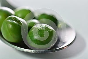 Close-up peas in spoon on a white background.