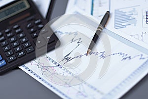 Close up.pen, financial chart and calculator on the businessman`s Desk