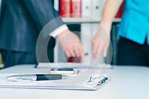 Close-up the pen lies on the documents. Business people hands pointing analyzing at the documents on the background